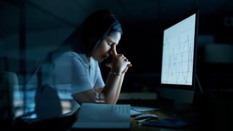 mujer estresada sentada frente a la computadora