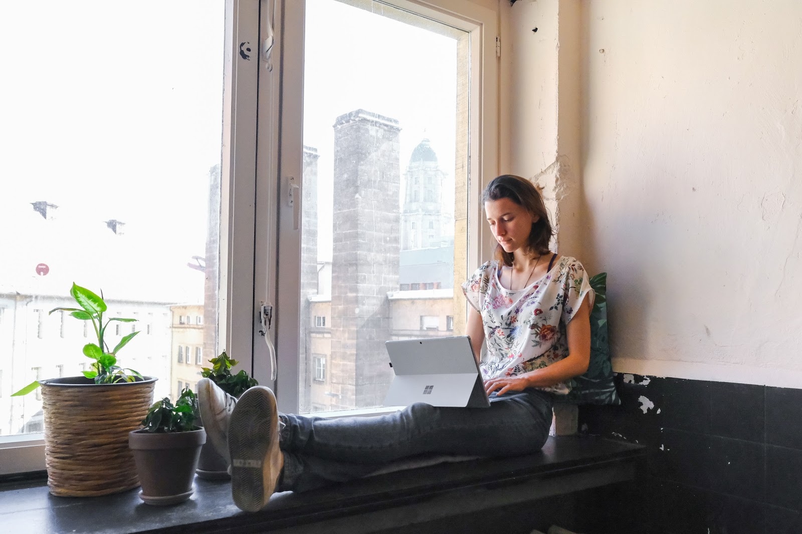 Jobs for introverts: A woman sits in a window and works on her laptop