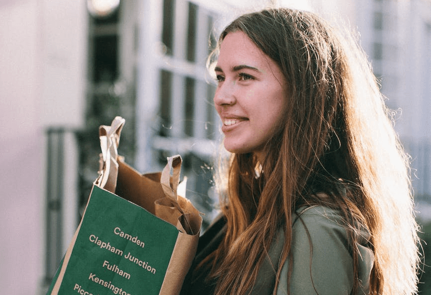 Mujer sonriente sosteniendo una bolsa de comestibles