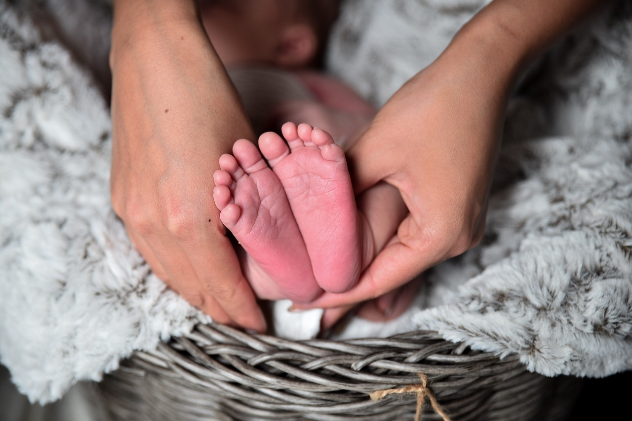 Las manos de una madre sostienen los pies de un bebé