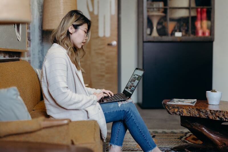 Encuestas por dinero: una mujer se sienta en su sofá y trabaja en su computadora portátil
