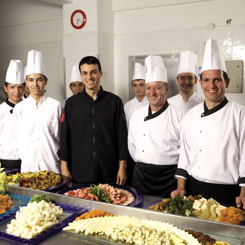 Chefs de restaurantes sonriendo detrás de platos de comida en la mesa y listos para la apertura del restaurante