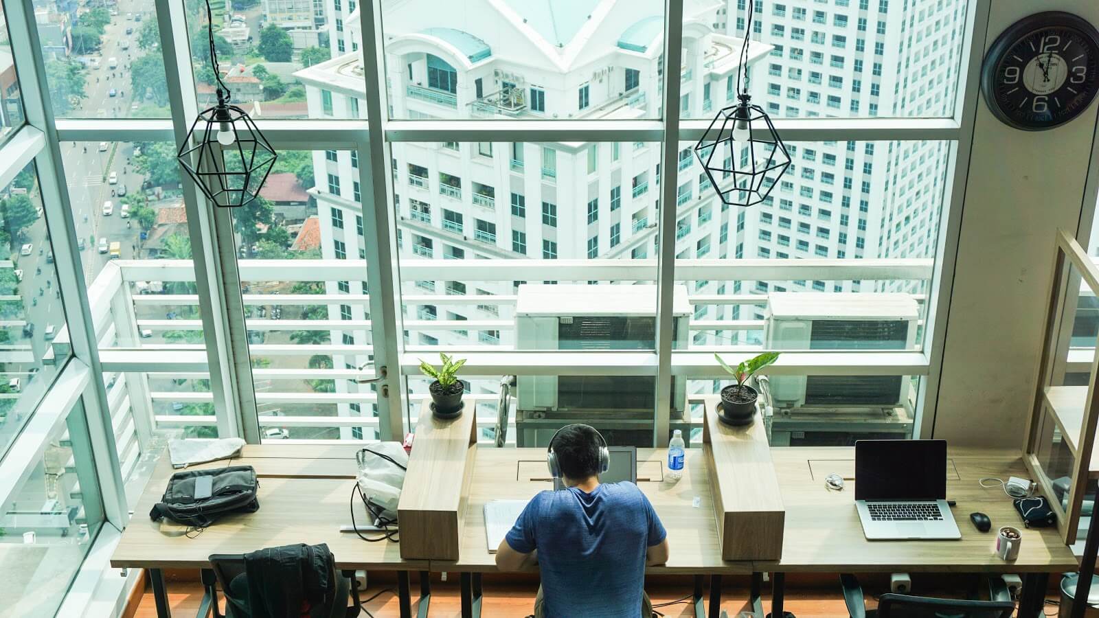 Hombre trabajando en un escritorio en un edificio de gran altura con amplias vistas de la ciudad 