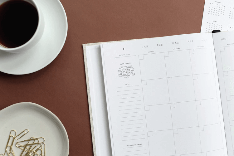 Escritorio con un calendario, taza de café y clips 