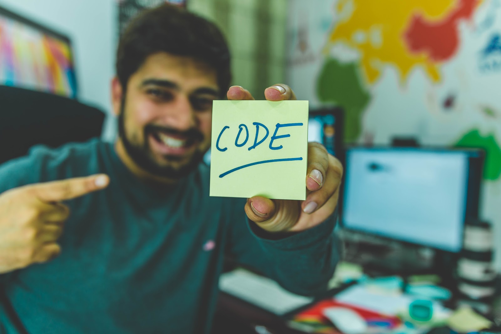 hombre sosteniendo una nota adhesiva con la palabra "código"