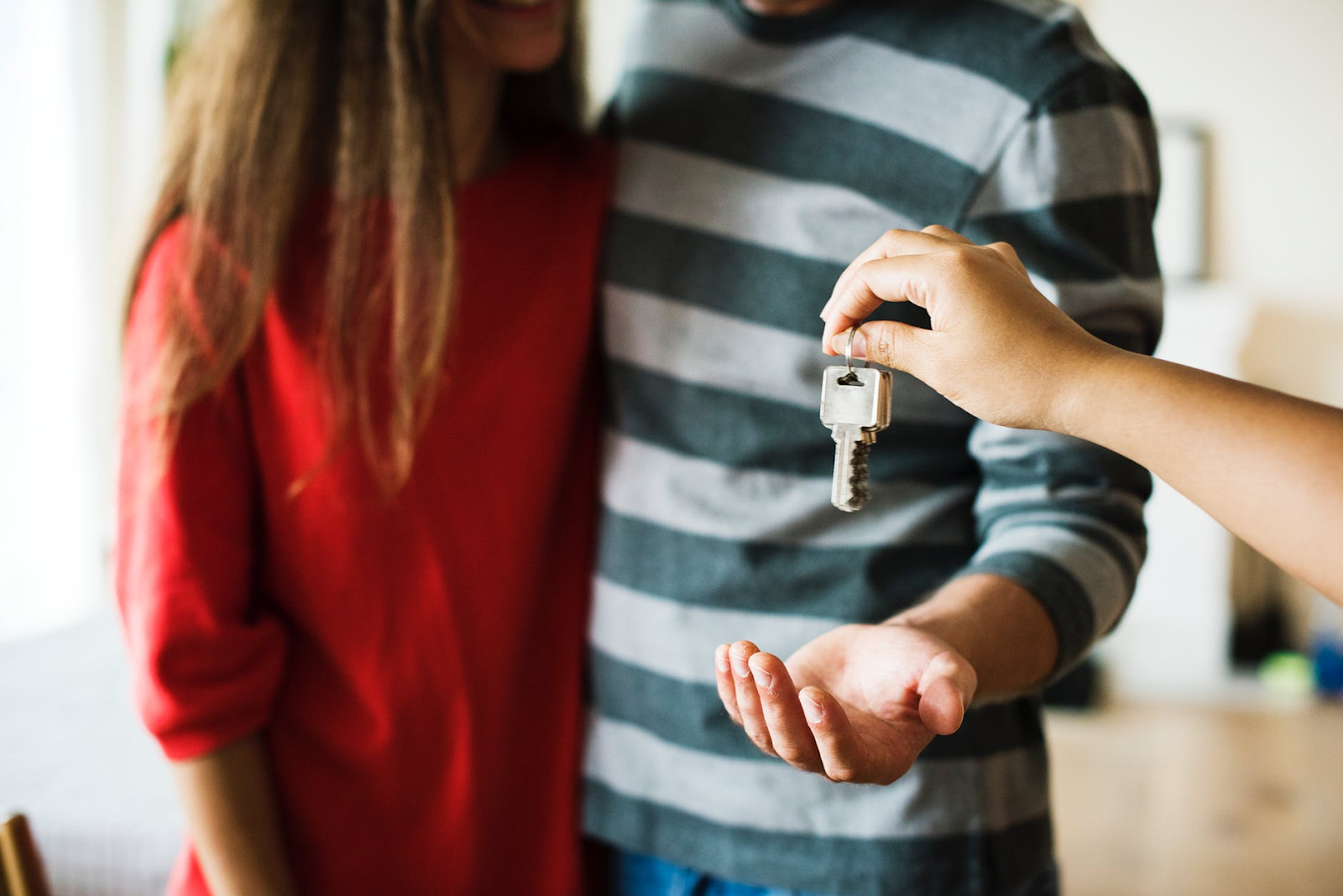 Cómo calcular el patrimonio neto: una mano le da a una pareja las llaves de una casa
