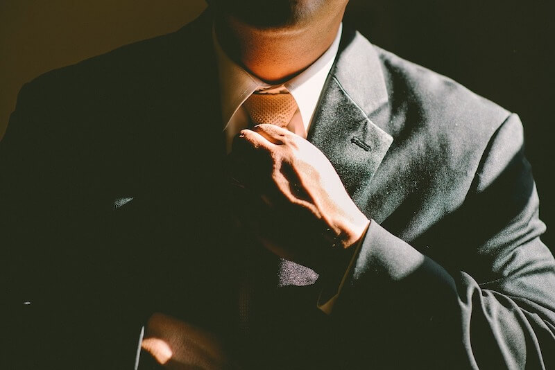 Cómo responder preguntas comunes de la entrevista: Un hombre endereza su corbata