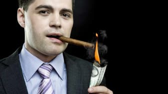 imagen de un tipo rico encendiendo un cigarro con un billete de dólar