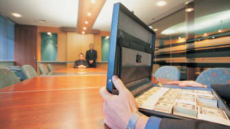 imagen de un hombre en un escritorio largo con un maletín lleno de dinero en efectivo