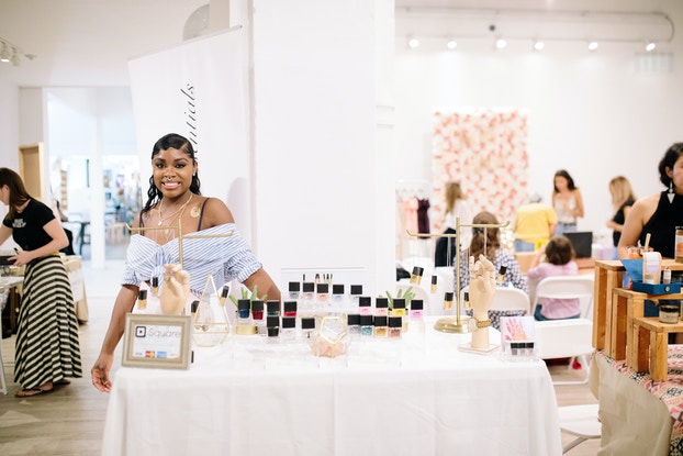   Tanisha Lawrence, fundadora de Law Beauty Essentials, de pie en una exhibición de productos.