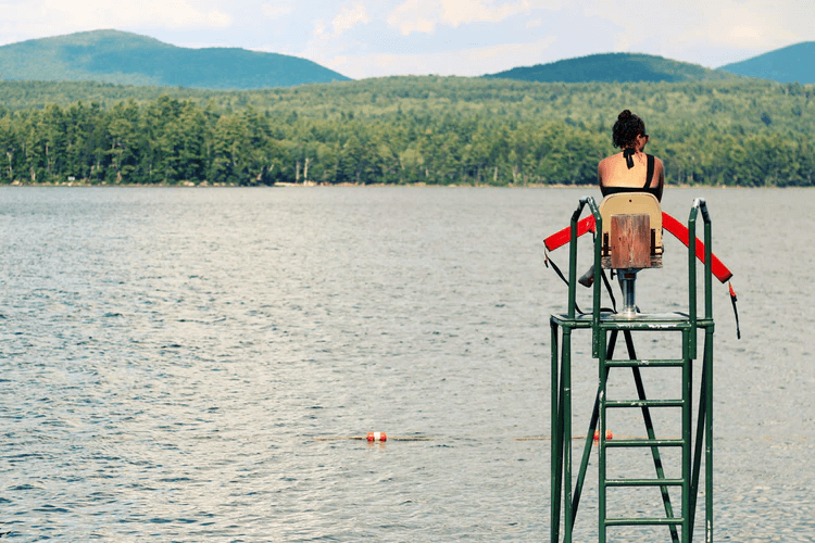 Socorrista sentado en la torre de vigilancia en un lago