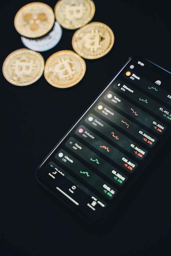 Monedas dispersas cerca de teléfono inteligente con gráficos financieros en pantalla