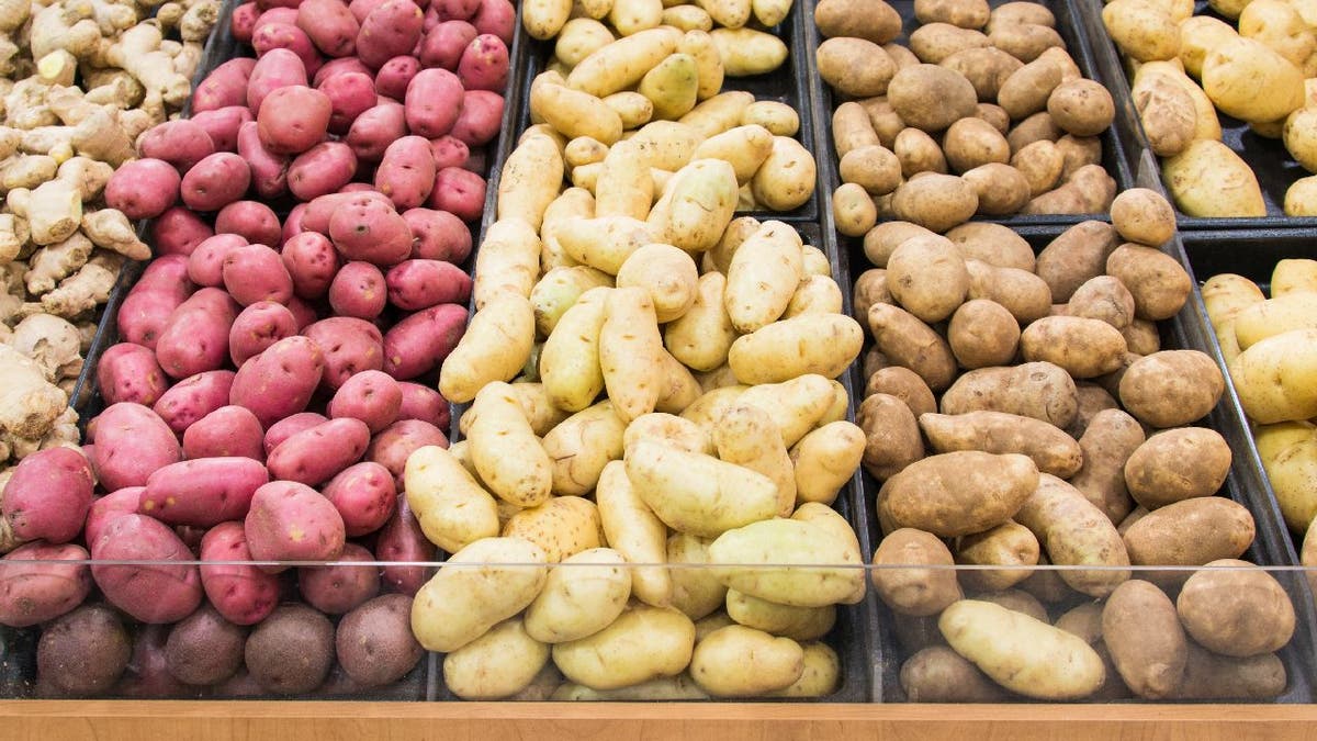 La tienda de comestibles muestra diferentes colores y variedades de papas para que las personas las seleccionen.